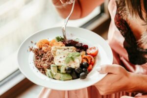 Woman eating a healthy meal with fruits and vegetables, showing a sustainable approach to nutrition.