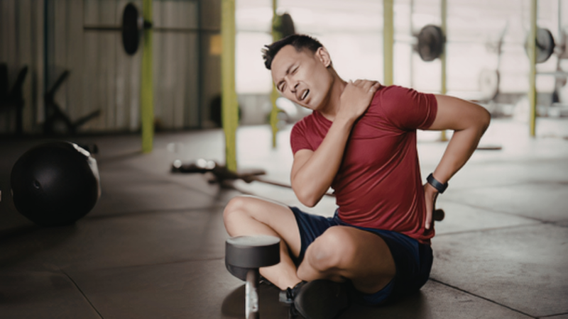 man sitting in gym looking tired after intense workout reflecting on overtraining and lack of fitness balance